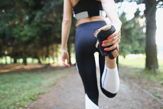 Atleta feminina amassando a perna no treinamento esportivo no parque fechado