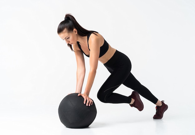 Atleta feminina em forma e forte malhando com uma bola medicinal para obter melhor força e estabilidade do núcleo