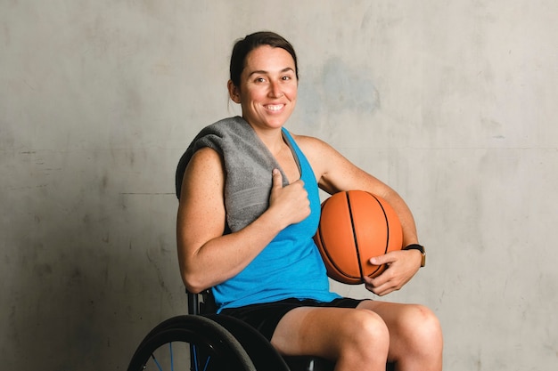 Atleta feminina feliz em uma cadeira de rodas com uma bola de basquete