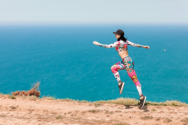 Atleta feminina na costa do mar realiza exercícios antes do treino e corrida