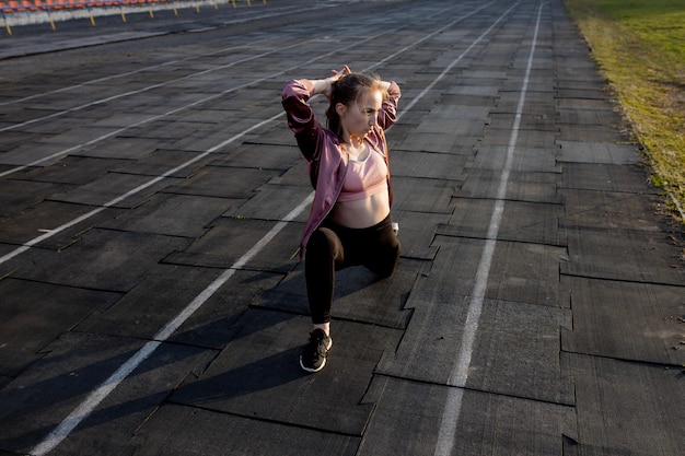 Foto atleta feminina preparando as pernas para um treino de cardio corredora de fitness fazendo uma rotina de aquecimento corredora feminina aquecendo-se atleta ao ar livre se esticando e aquecendo em uma pista de corrida em um estádio