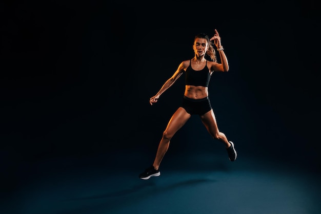 Atleta feminina saltando contra um fundo preto