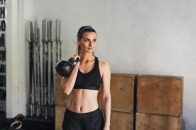 Atleta feminina se exercitando com kettlebell no ginásio