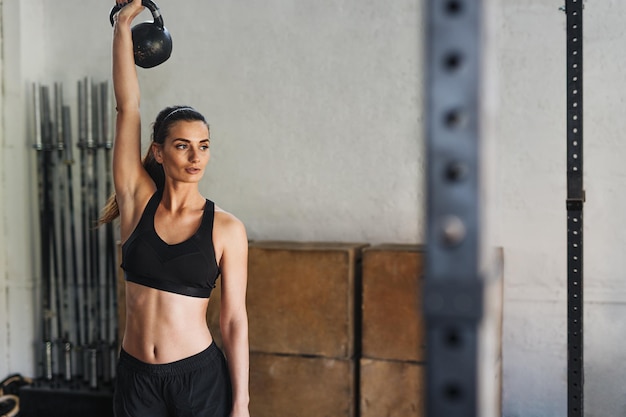 Atleta feminina se exercitando com kettlebell no ginásio