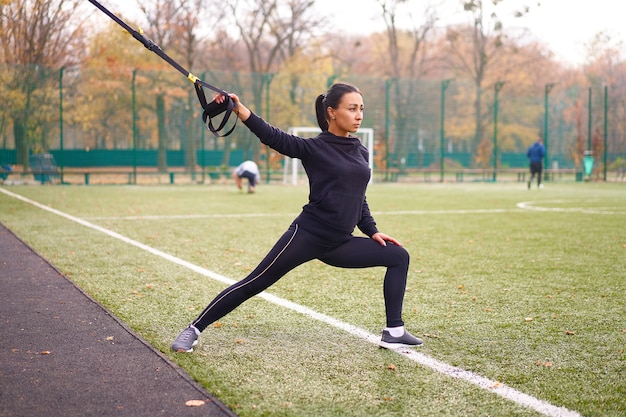 Atleta feminina treinando usando trx no campo esportivo