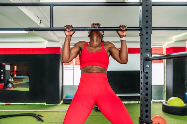 Atleta fisiculturista negra em um ginásio de esportes fazendo um exercício de barra para trás. conceito de fortalecimento do corpo na academia