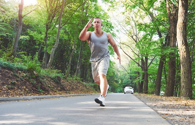 Atleta de fitness hombre trotar en la naturaleza durante la puesta de sol.