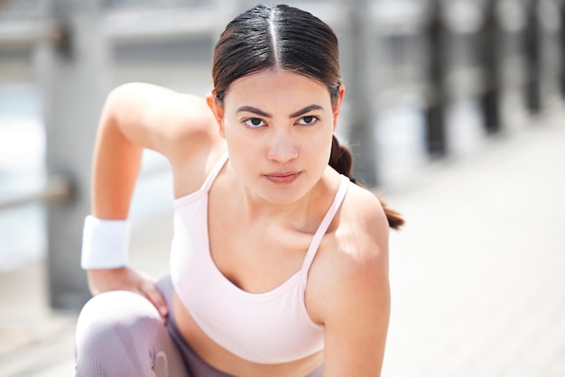 Atleta de fitness y mujer haciendo un ejercicio de estiramiento antes de hacer ejercicio o correr en el paseo marítimo Motivación fuerte y chica preparándose para entrenar para maratón deportivo en la naturaleza junto al mar o al mar