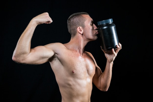 Foto atleta flexionando os músculos ao beijar o recipiente