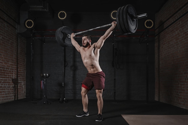 Atleta en forma cruzada levantando pesas en el gimnasio