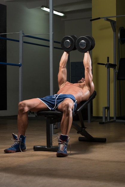 Atleta en forma trabajando en rizos de concentración con mancuernas en el pecho