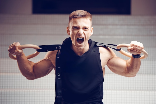 Atleta ginasta no ginásio em treinamento com anéis de ginástica Conceito de esporte e ginástica