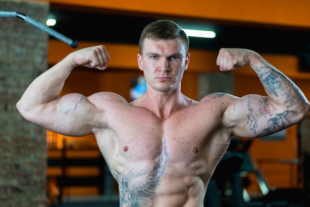 Atleta guapo en el gimnasio demuestra los músculos bombeados. estilo de vida deportivo.