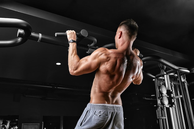 El atleta hace un pullup en la barra horizontal un hombre en gran forma está haciendo pullups en la