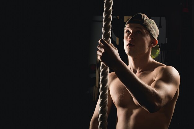 Atleta haciendo ejercicio de escalada de cuerda de fitness en gimnasio gimnasio entrenamiento