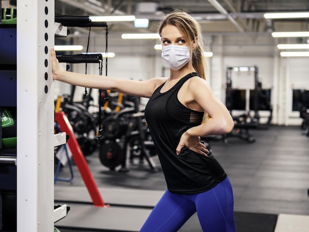 Atleta haciendo ejercicio en el gimnasio durante una pandemia con mascarilla protectora