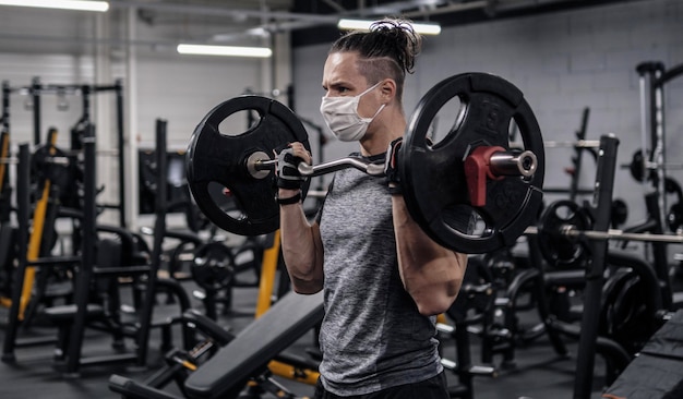 Atleta haciendo ejercicio en el gimnasio durante una pandemia con mascarilla protectora