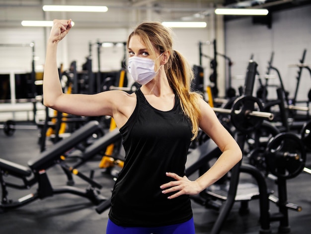 Atleta haciendo ejercicio en el gimnasio durante una pandemia con mascarilla protectora