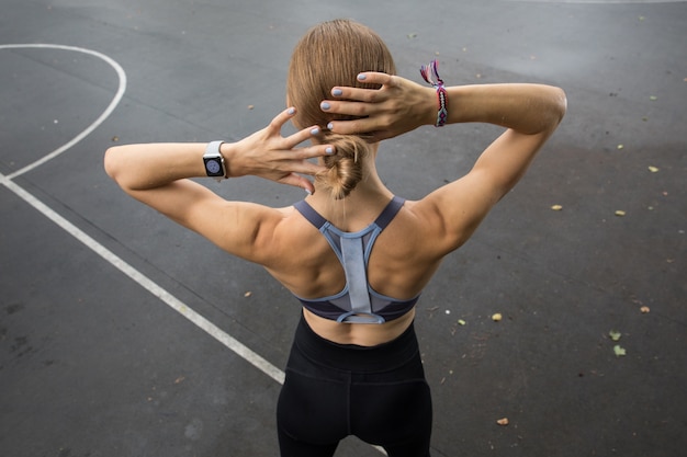 Foto atleta con una hermosa figura calentando antes de entrenar en el parque.