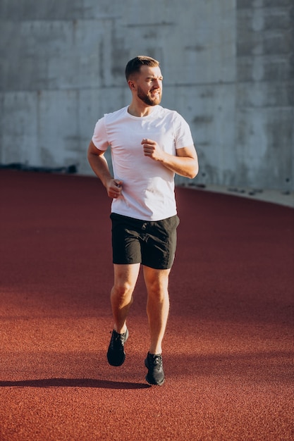 Foto atleta hombre corriendo en el estadio por la mañana