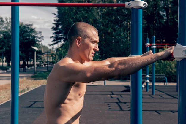 Atleta hombre entrenado fuerte posando en el campo de deportes cuerpo fuerte musculoso