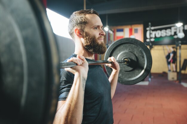 Atleta homem com barba fazendo exercícios em uma academia