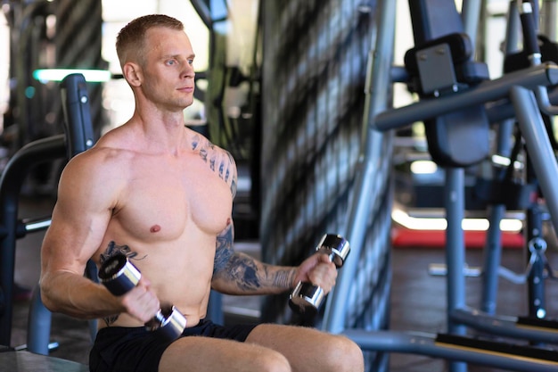 atleta homem fisiculturista malhando academia de treinamento segurando haltere ganhando peso bombeando músculos