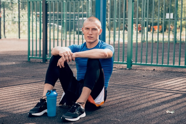 Atleta homem sentado no chão após treino ao ar livre