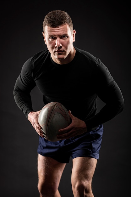 Foto atleta jogador de rúgbi posando com bola