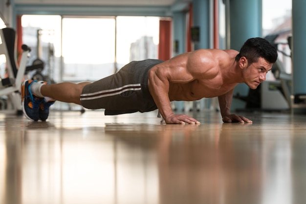 Atleta jovem adulto fazendo flexões como parte do treinamento de musculação