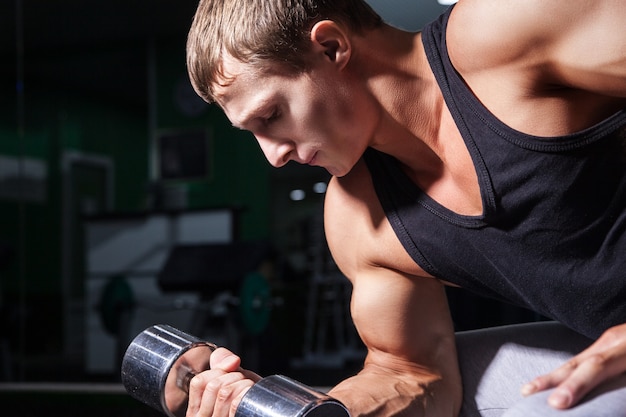 Atleta jovem e bonito fazendo exercícios de concentração na academia