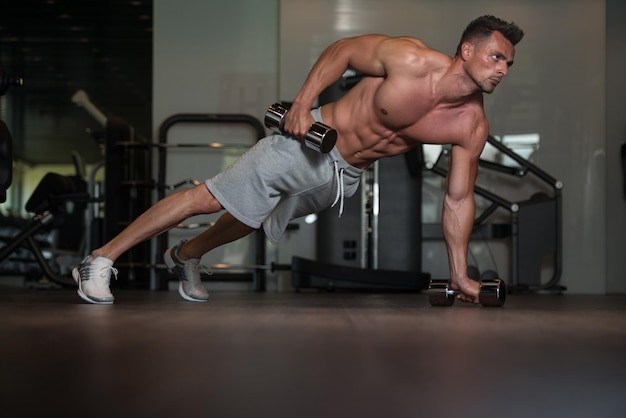 Atleta jovem fazendo flexões com halteres como parte do treinamento de musculação