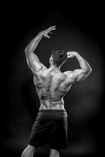 Atleta jovem sexy, posando em um espaço preto. Fitness, musculação, preto e branco.