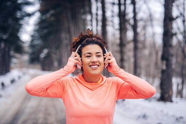 Atleta joven poniéndose los auriculares al aire libre