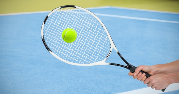 Atleta jugando al tenis con una raqueta contra la imagen compuesta del campo de tenis