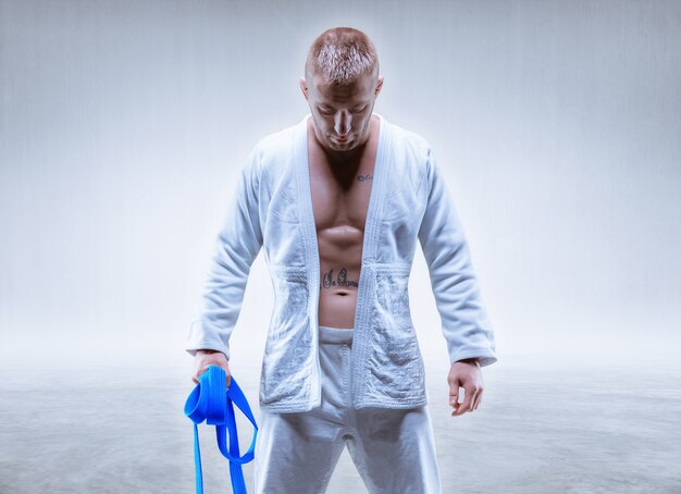 El atleta con un kimono con un cinturón azul se encuentra con la cabeza gacha. El concepto de karate y judo. Técnica mixta