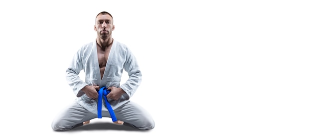 Foto el atleta en un kimono con un cinturón azul se sienta y espera al oponente. concepto de karate, sambo, jujitsu. técnica mixta