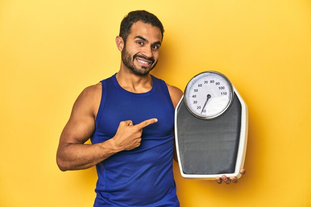 Foto atleta latino em forma segurando uma balança focada em objetivos de fitness e saúde