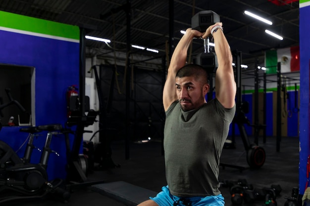 Atleta latino haciendo ejercicio de tríceps en un gimnasio con pesas