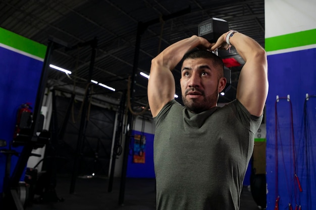 Atleta latino haciendo ejercicio de tríceps en un gimnasio con pesas