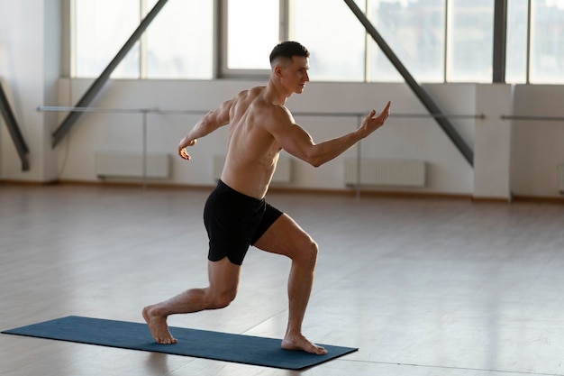 Atleta latino musculoso haciendo yoga en un amplio gimnasio en colchoneta realizando ejercicios Estilo de vida saludable