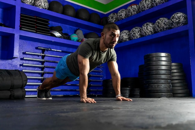 Atleta latino con ropa deportiva en un gimnasio haciendo tablón alto