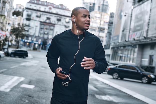 Atleta latinoamericano corriendo en la ciudad por la mañana