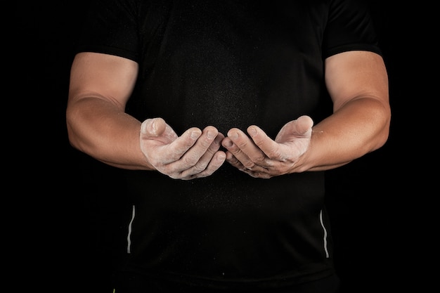 Atleta masculino adulto frota polvo blanco con magnesia antes de eventos deportivos