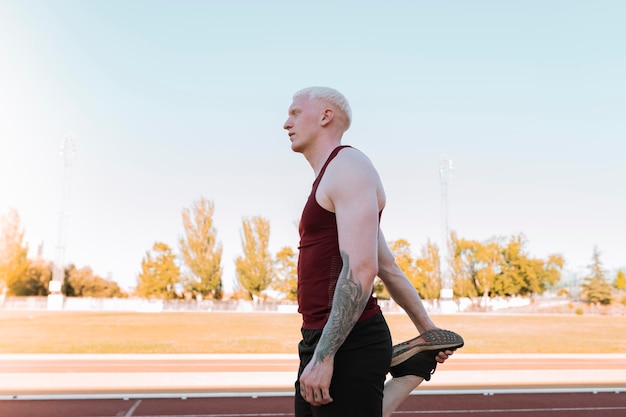 Atleta masculino albino paralímpico, no alongamento da pista de atletismo