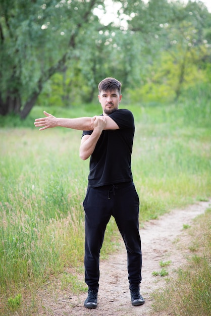 Un atleta masculino amasa las articulaciones de sus manos en la naturaleza.