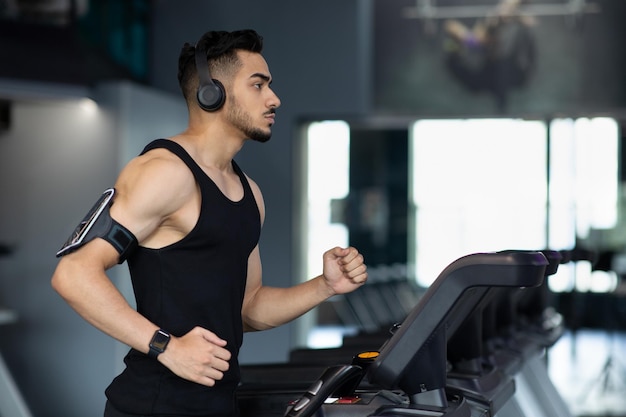 Atleta masculino árabe muscular que usa auriculares inalámbricos