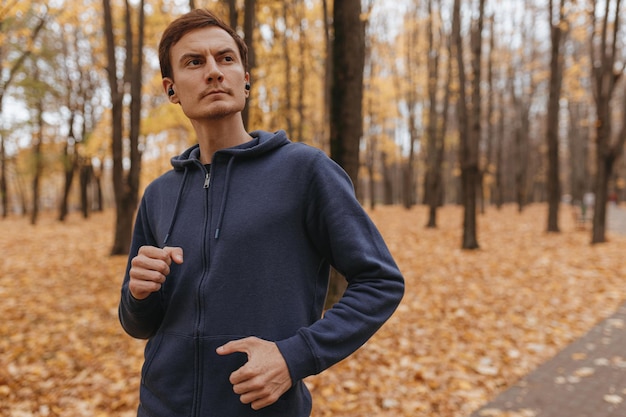 Atleta masculino confiante em roupas ativas correndo no parque outono