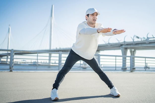 Atleta masculino corriendo en la calle entrenando activamente y estirándose en ropa deportiva