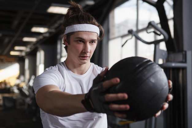 Atleta masculino con diadema mirando enfocado haciendo ejercicio con balón medicinal